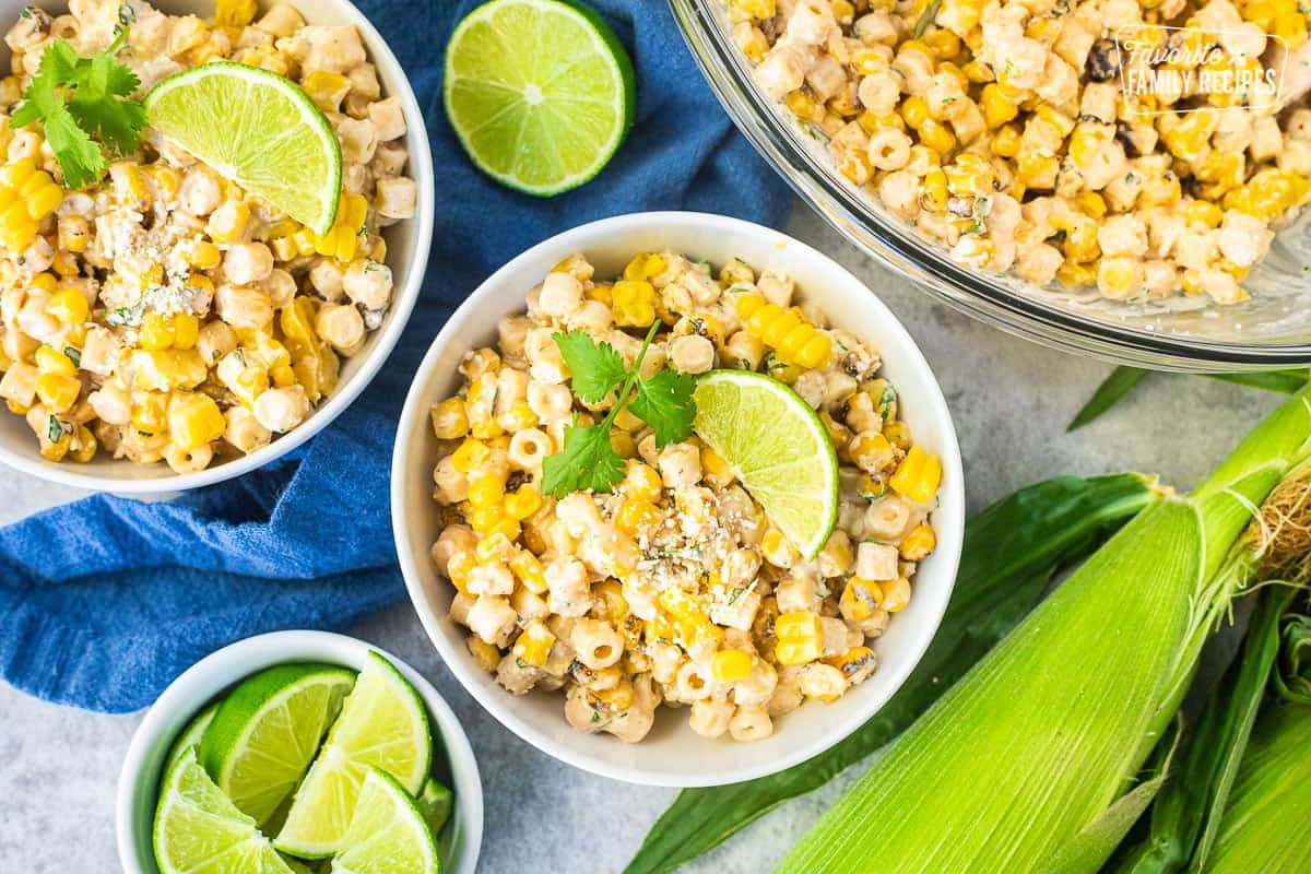 Elote Pasta Salad with corn, pasta, cojita cheese, lime and cilantro in two small bowls.
