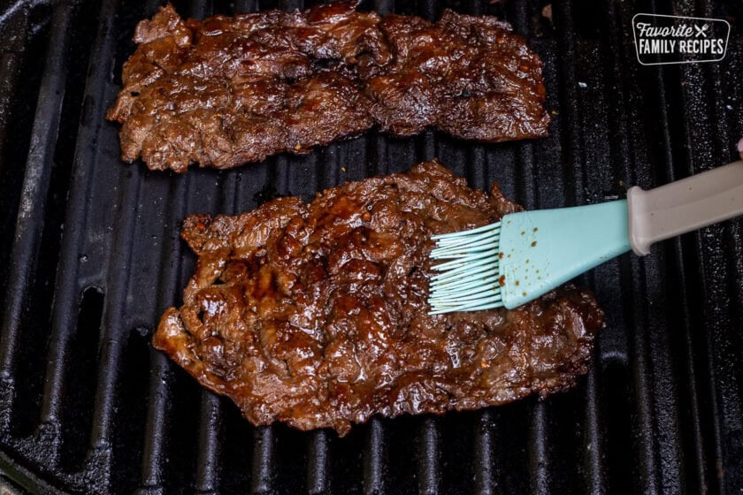 Grilling and basting Hawaiian Beef Teriyaki on the grill.