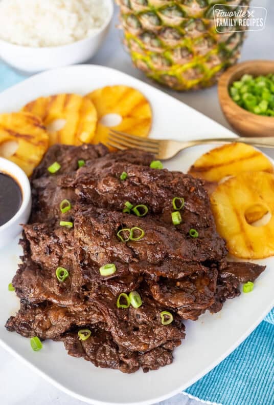 Hawaiian Beef Teriyaki on a plate garnished with green onion and grilled pineapple slices on the side.
