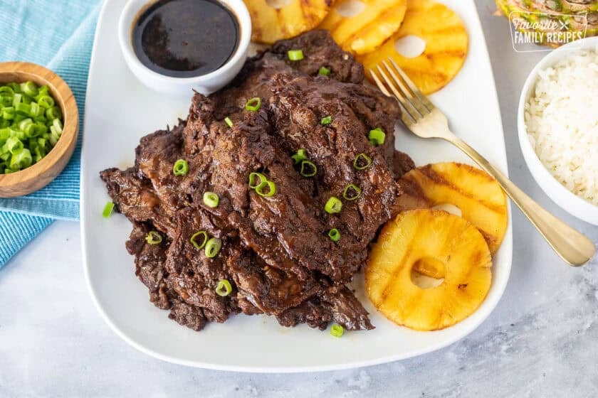 Hawaiian Beef Teriyaki on a plate garnished with green onion and grilled pineapple slices on the side.