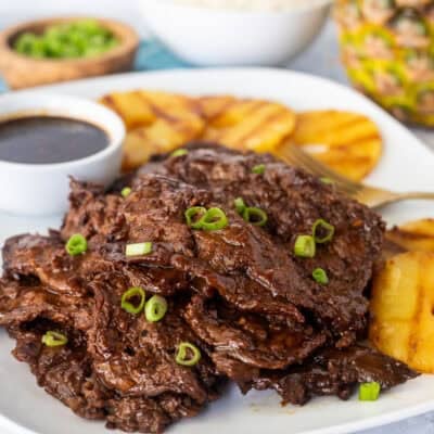 Hawaiian Beef Teriyaki on a plate garnished with green onion and grilled pineapple slices on the side.