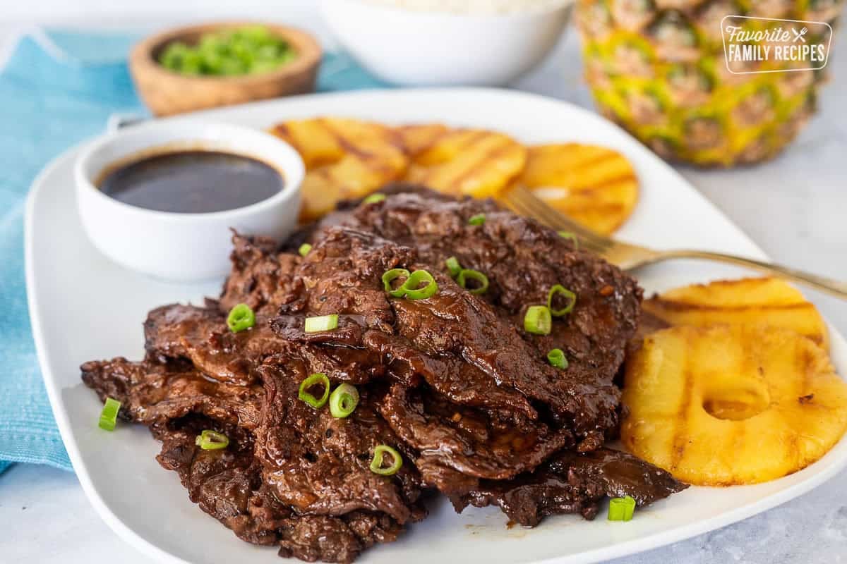 Hawaiian Beef Teriyaki on a plate garnished with green onion and grilled pineapple slices on the side.