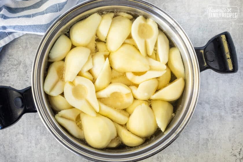 Large pot with sugar syrup and prepared pears.