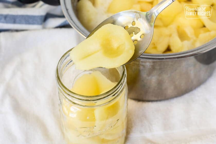 Spooning prepared pear into canning jar.