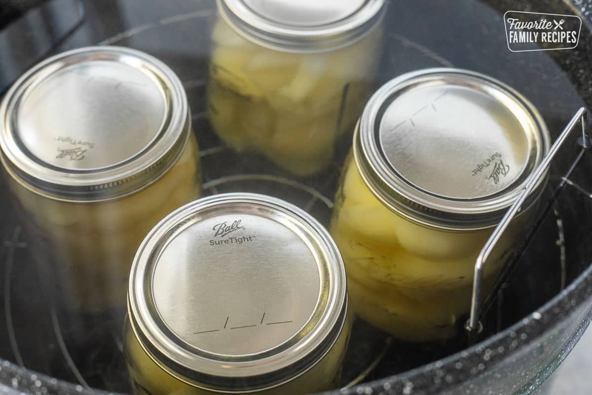 Canning pot with canned pears submerged in hot water with trivet.