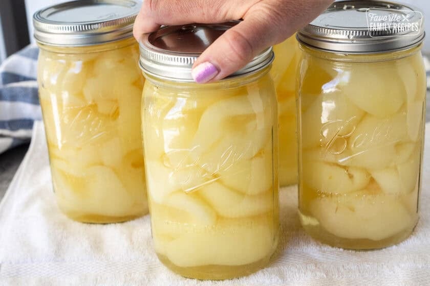 Twisting lid onto canned pears.