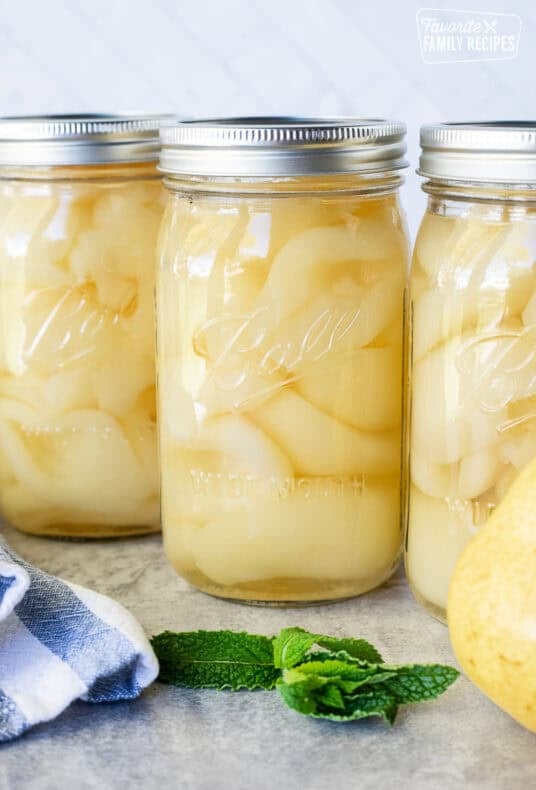 Canning jars lined up with fresh pears.