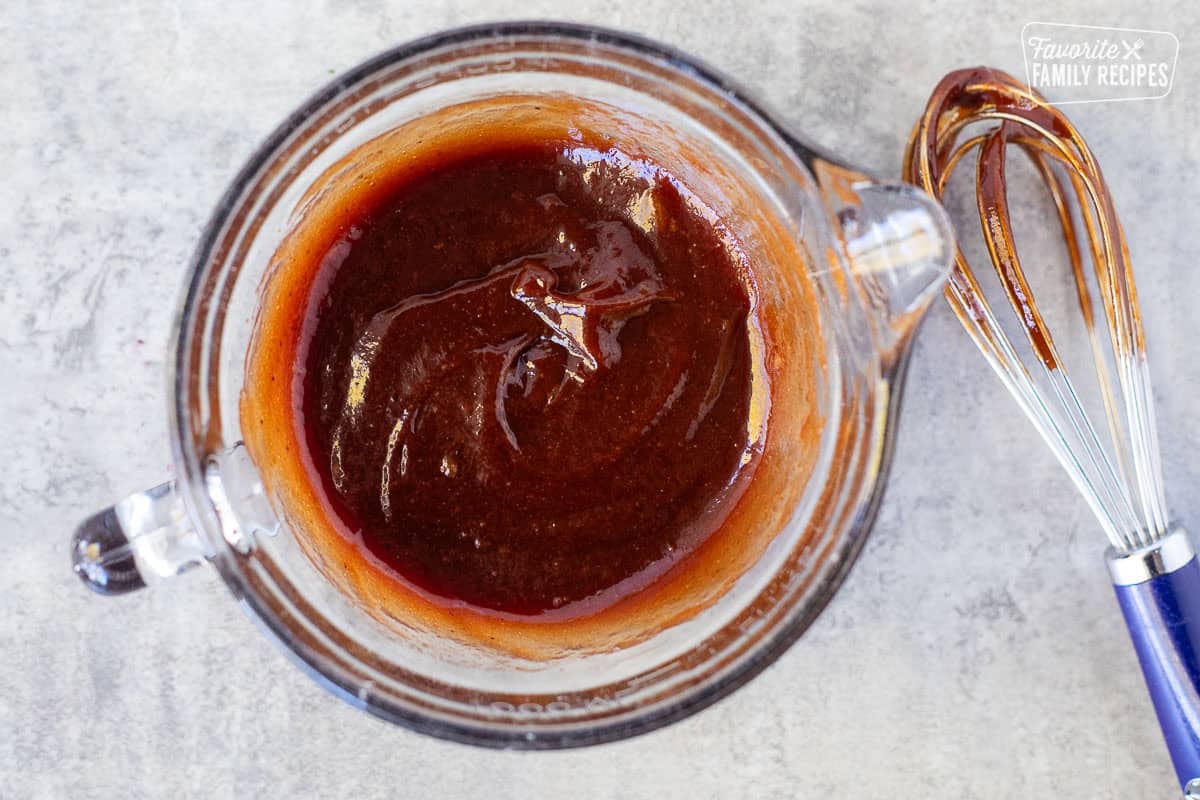 BBQ sauce combined in a glass bowl. Whisk on the side.