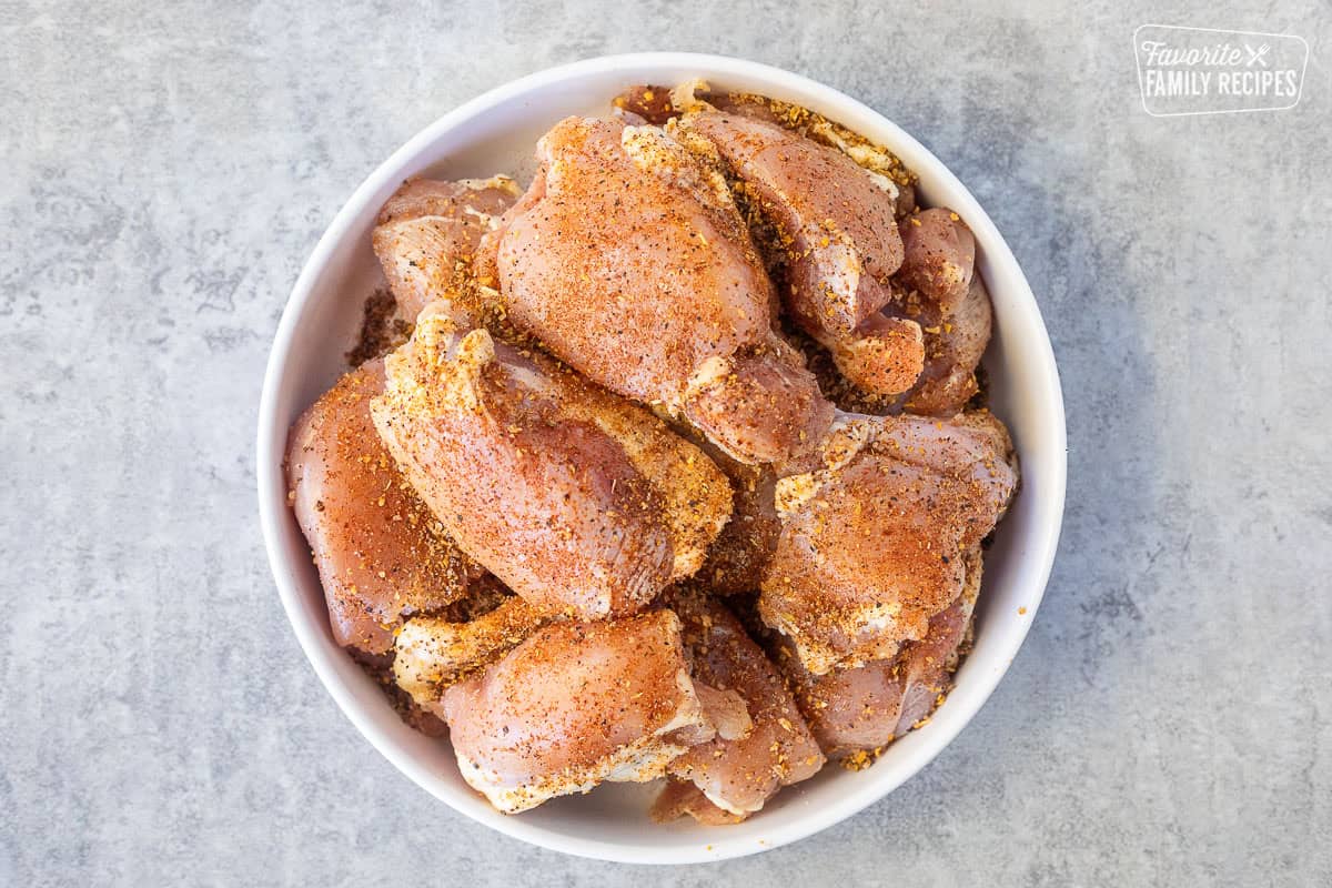 Seasoned chicken thighs in a bowl.