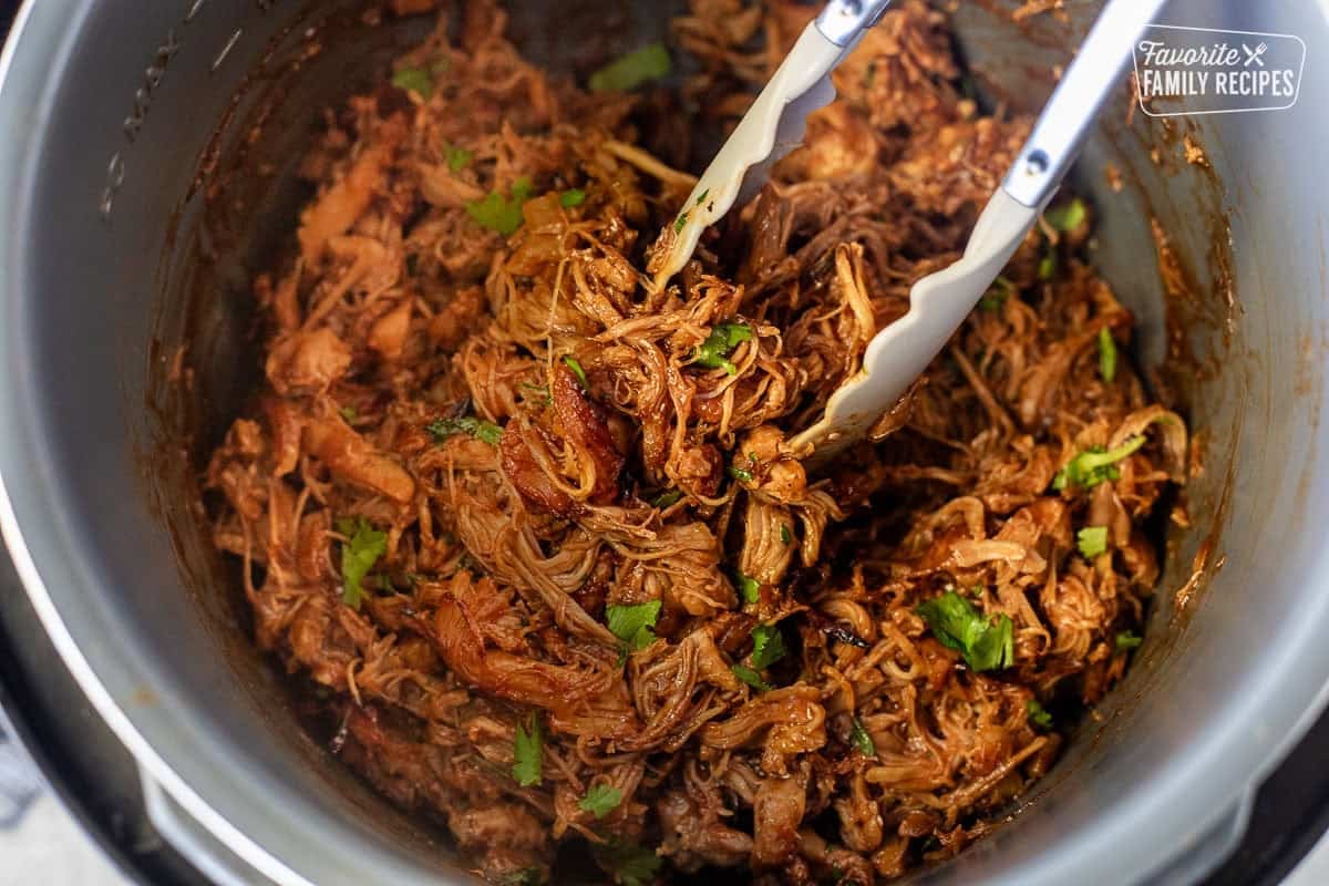 Instant Pot BBQ Chicken with tongs in an instant pot and garnish with cilantro.