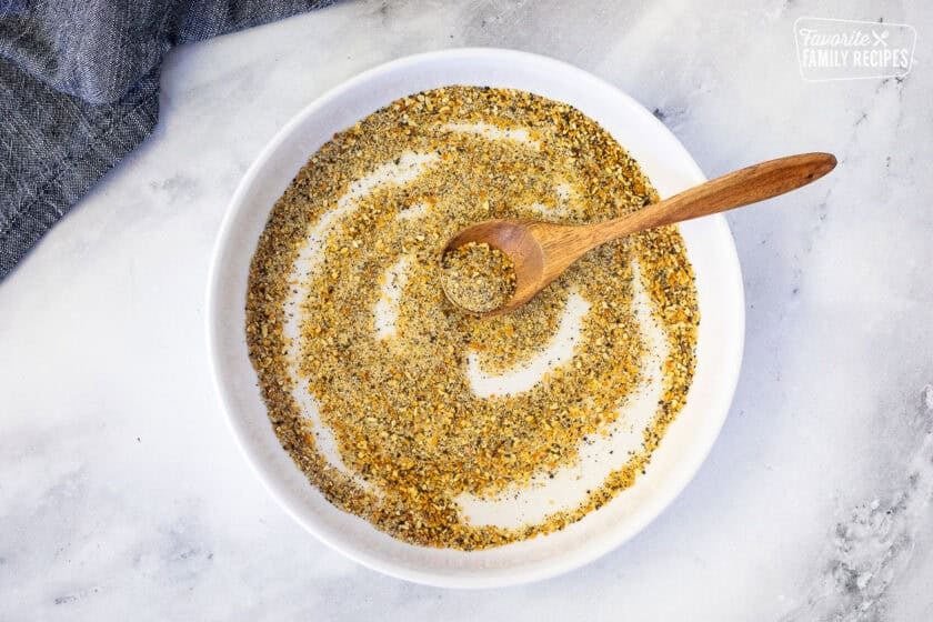 Bowl with seasonings combined with a spoon.
