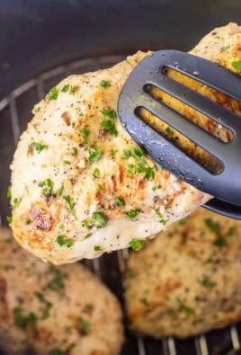 Tongs holding a Chicken breast from the instant pot.