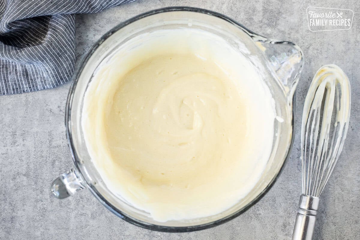 Glass mixing bowl with pancake batter from scratch. Whisk on the side.