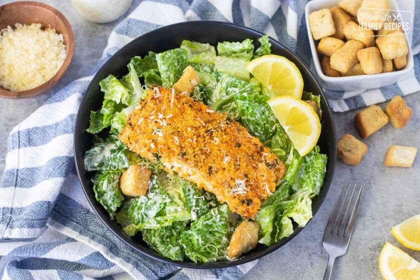 Salmon Caesar Salad with croutons and lemon wedges.