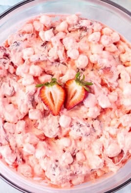 Strawberry fluff salad and a large mixing bowl with fresh strawberries on top.