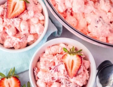 Two small bowls of strawberry fluff salad garnished with fresh strawberries.