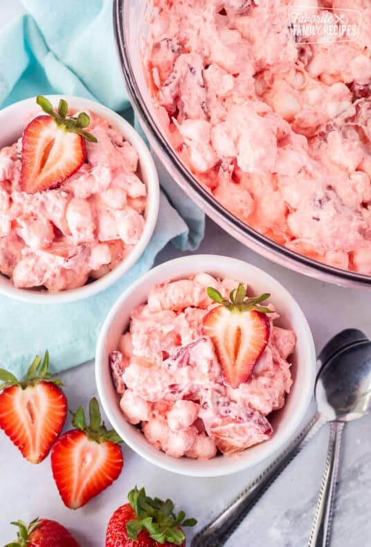 Two small bowls of strawberry fluff salad garnished with fresh strawberries.
