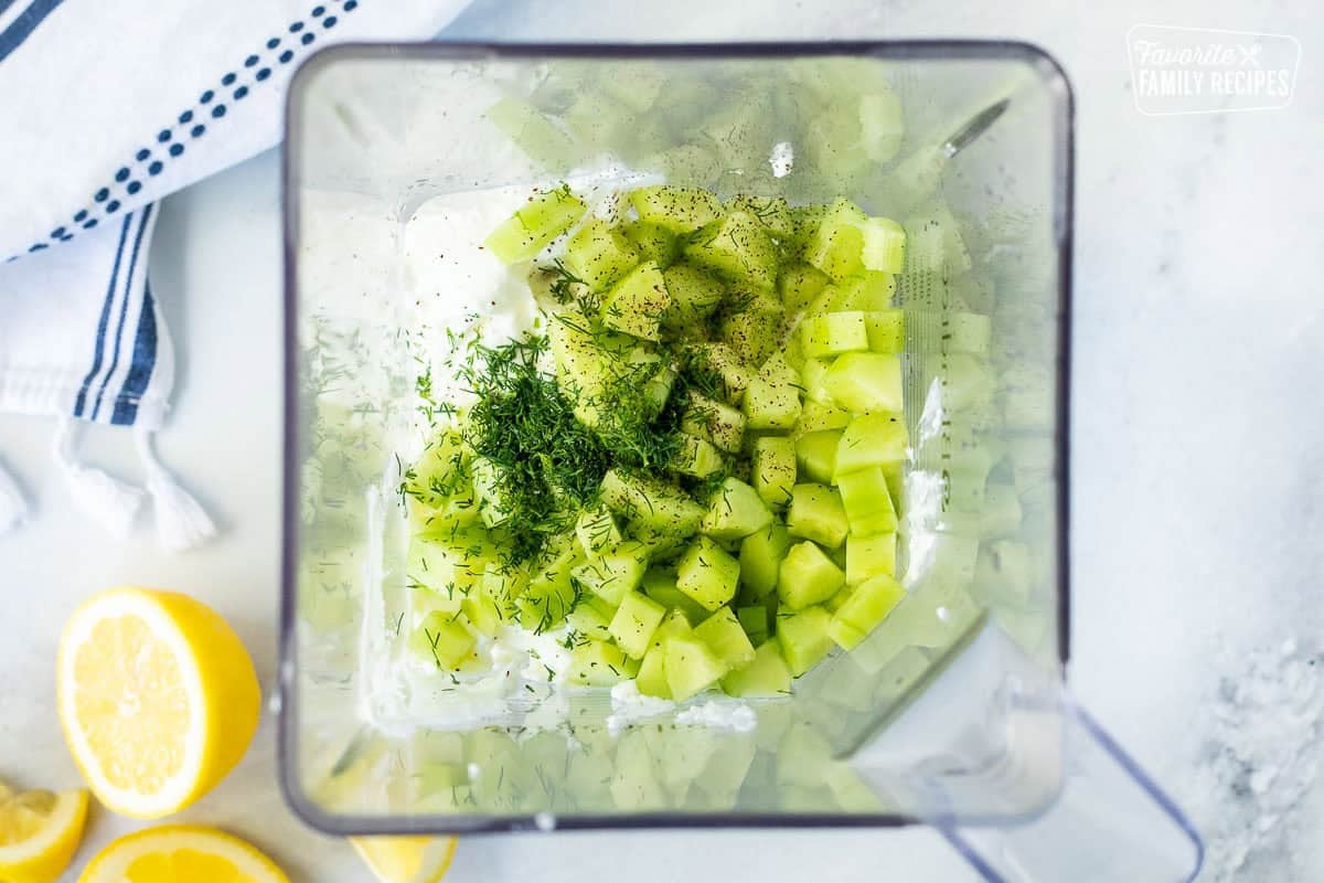 Blender with cut cucumbers, dill, salt, pepper, greek yogurt and lemon juice.