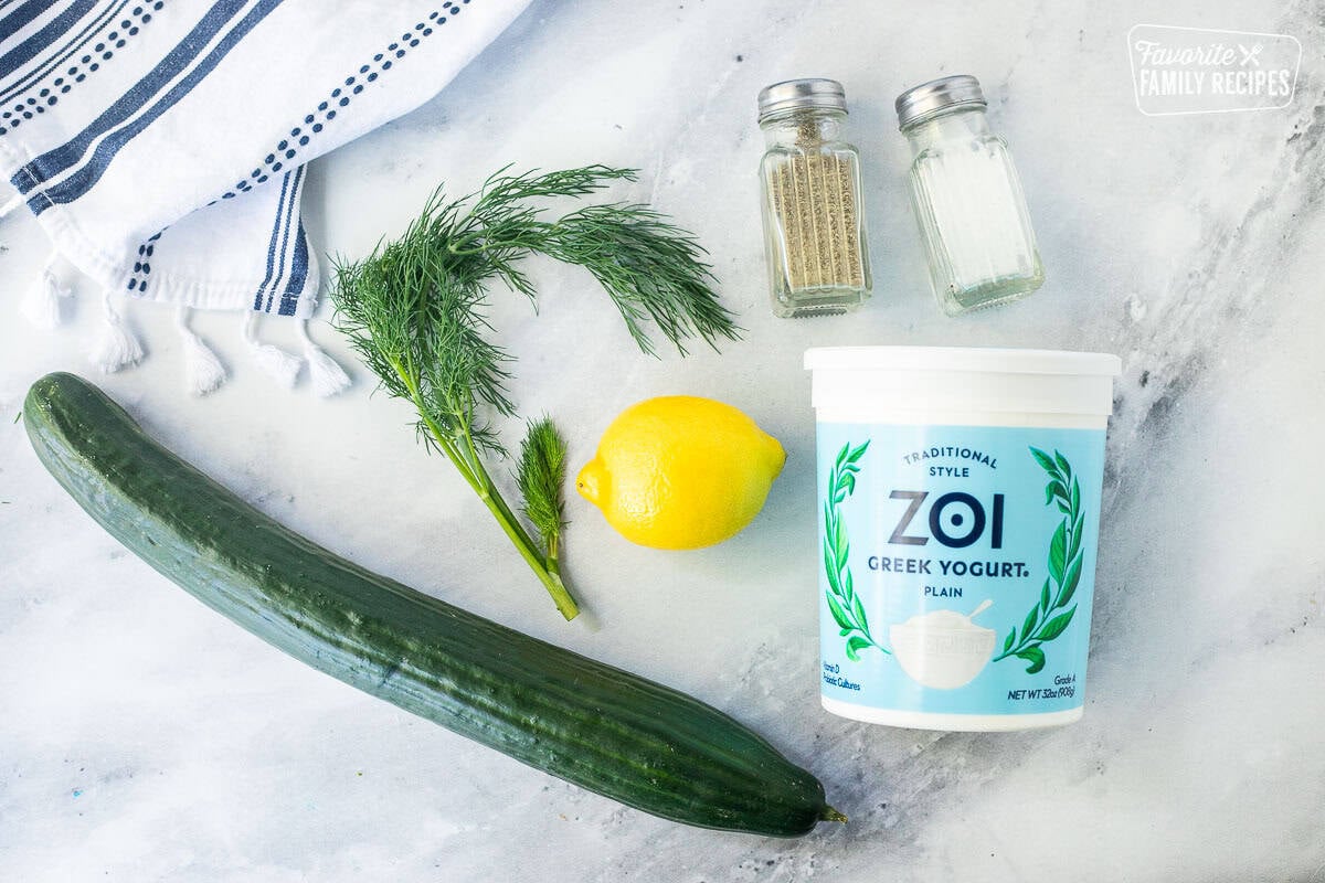 Ingredients to make Tzatziki sauce including plain greek yogurt, salt, pepper, dill, lemon and cucumber.