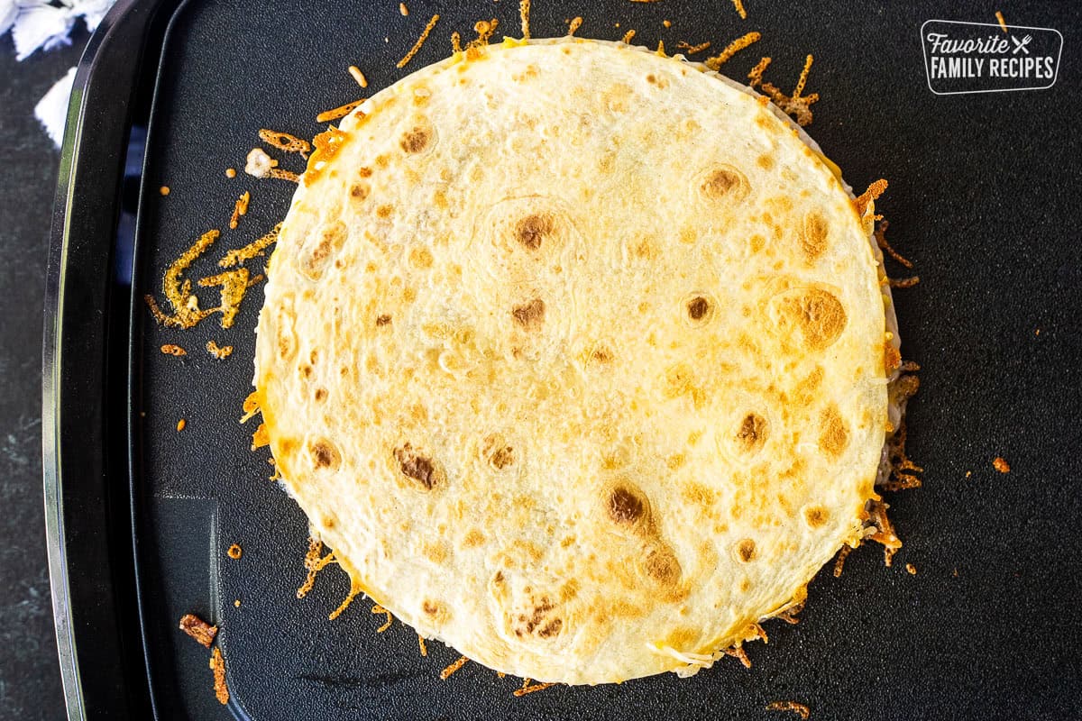 Golden brown Breakfast Quesadilla on a griddle.