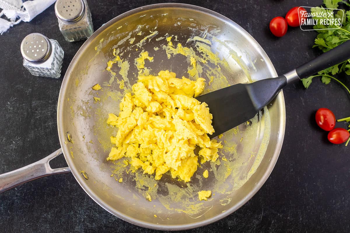 Skillet with scrambled eggs and spatula. Salt and pepper on the side.