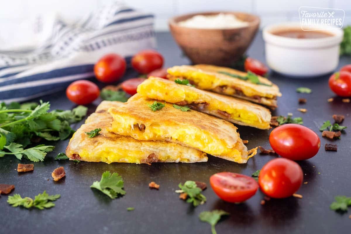 Four pieces of Breakfast Quesadilla garnished with cilantro and tomatoes.