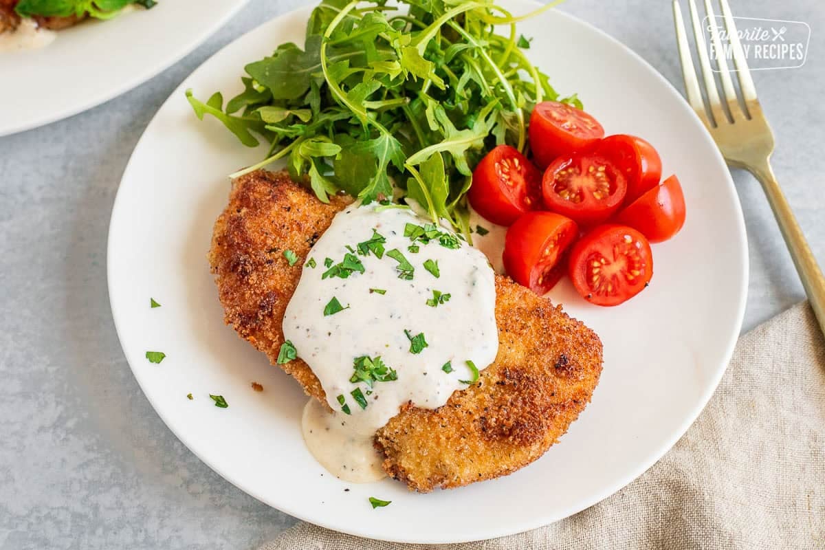 Breaded Chicken breasts with creamy basil sauce. Arugula salad and sliced cherry tomatoes on the side.