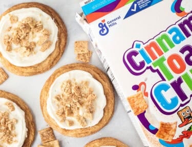 Box of Cinnamon Toast Crunch cereal next to frosted Cinnamon Toast Crunch cookies.