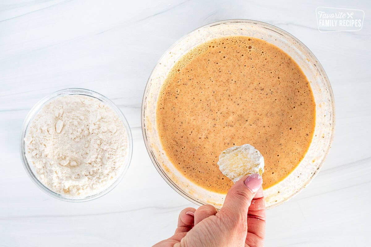 Pickle chip covered in flour over the bowl of batter.