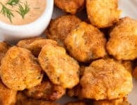 Fried pickles on plate with a small bowl of Sriracha dill dipping sauce.