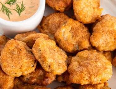 Fried pickles on plate with a small bowl of Sriracha dill dipping sauce.