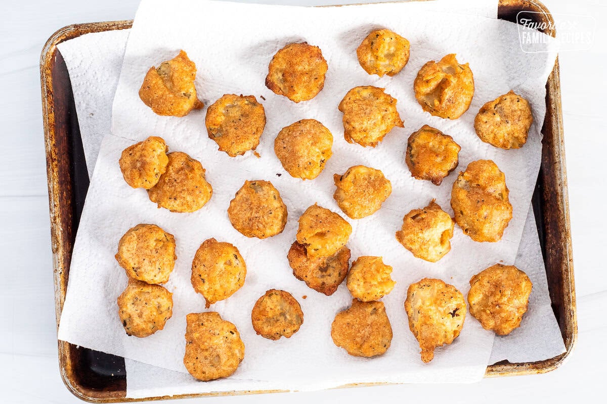 Fried pickles over paper towels on a sheet pan.