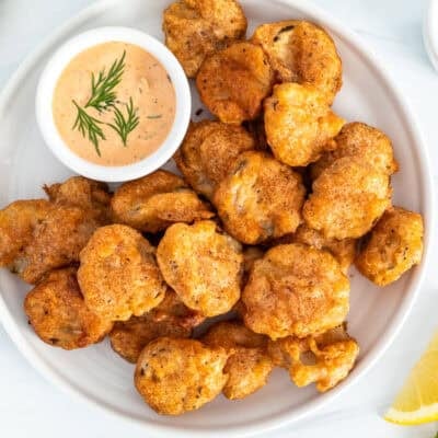 Fried pickles on plate with a small bowl of Sriracha dill dipping sauce.