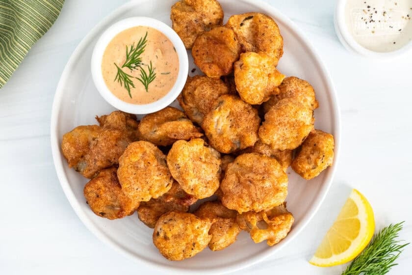 Fried pickles on plate with a small bowl of Sriracha dill dipping sauce.