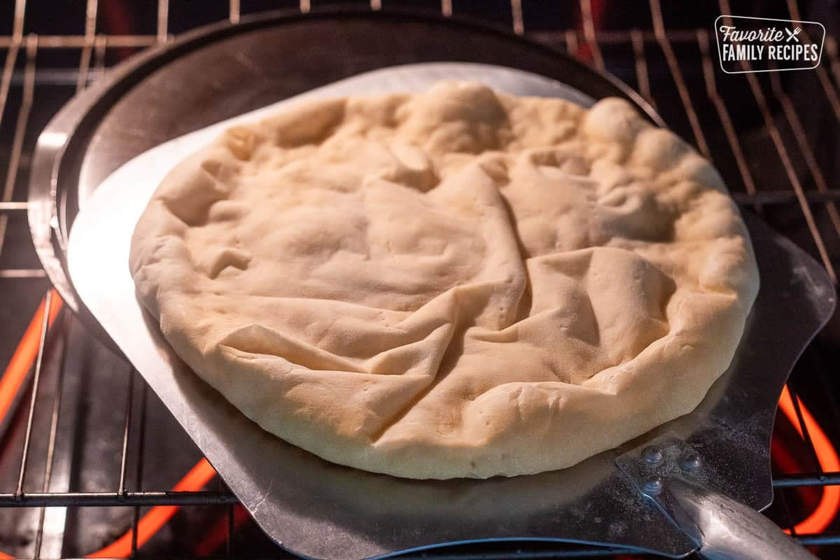 Removing pizza crust from the oven with pizza paddle.