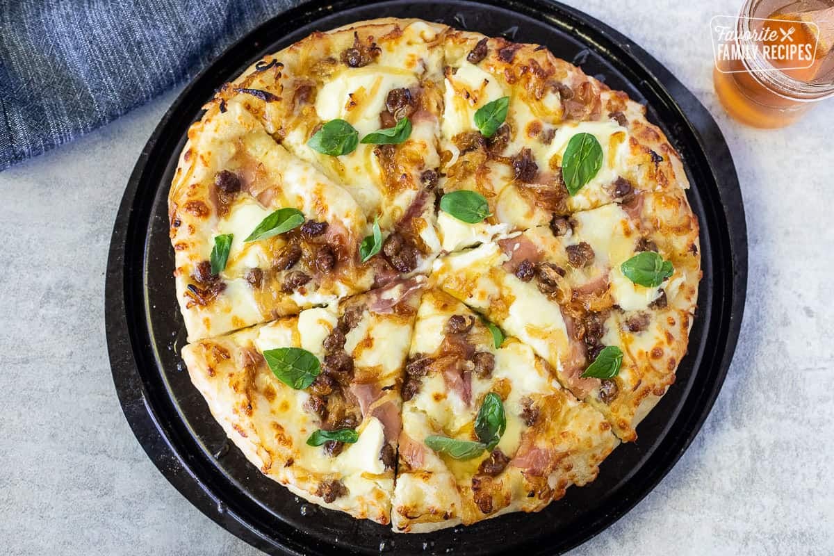 Baked hot honey pizza topped with drizzled hot honey and fresh basil leaves.