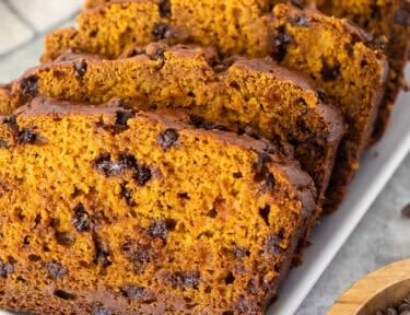 Six slices of pumpkin chocolate chip bread arranged on a platter.