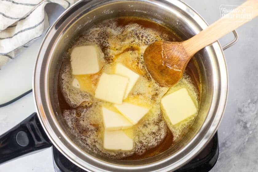 Saucepan with melting butter in hot caramel mixture and a wooden spoon.