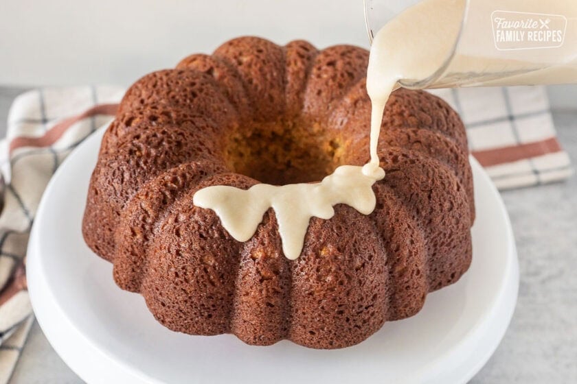 Pouring maple glaze on top of Sweet Potato Pound Cake on a cake stand.