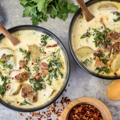 Two bowls of Zuppa Toscana soup with sausage, kale, bacon, potatoes and a creamy chicken broth. Bread sticks on the side.