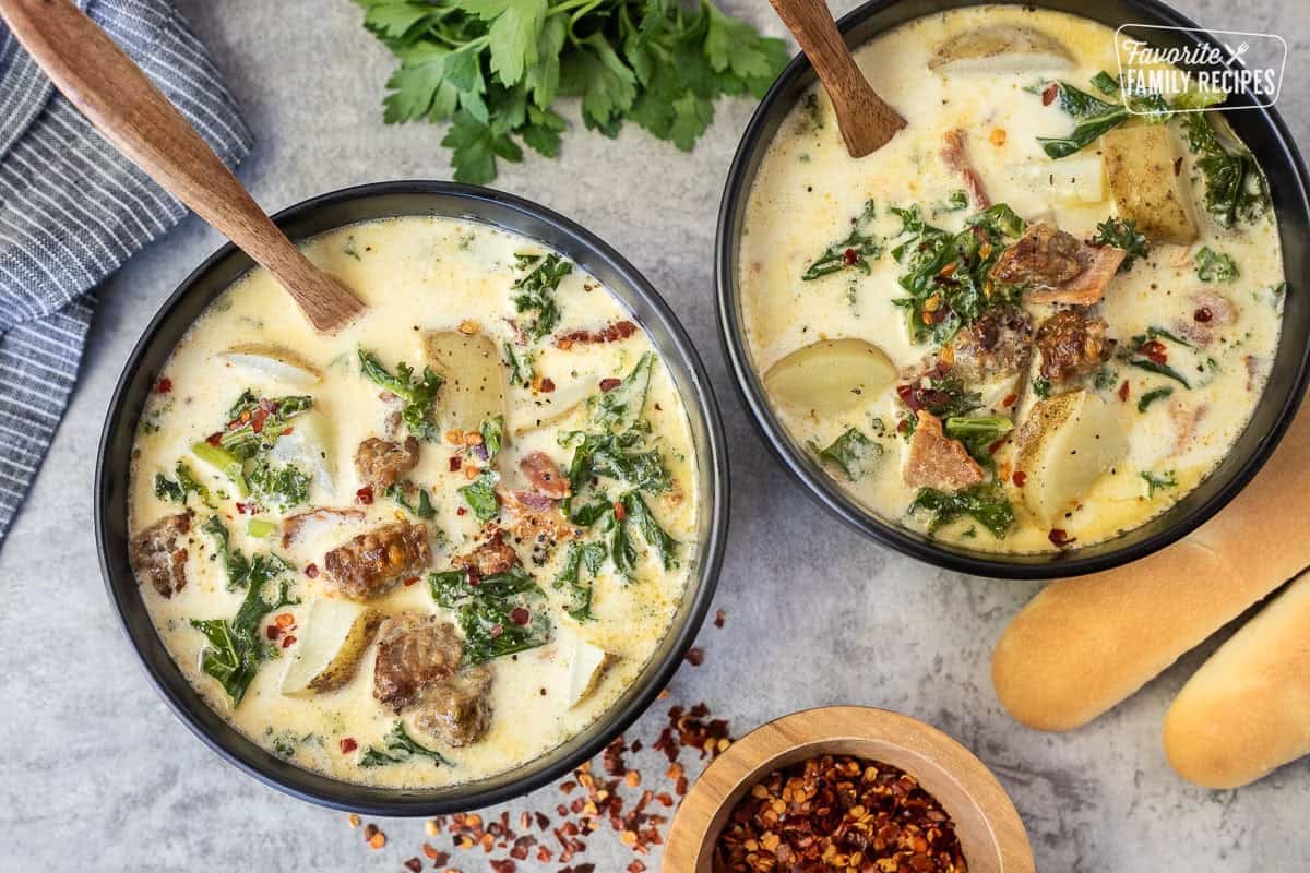 Two bowls of Zuppa Toscana soup with sausage, kale, bacon, potatoes and a creamy chicken broth. Bread sticks on the side.