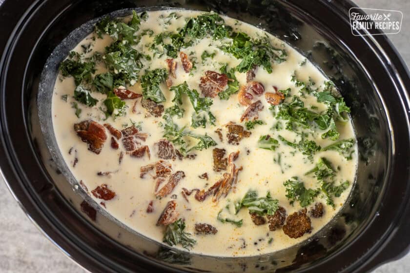 Crockpot with chicken broth, cream, kale, bacon and sausage pieces.