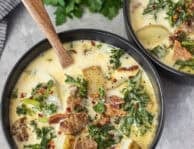 Two bowls of Zuppa Toscana soup with sausage, kale, bacon, potatoes and a creamy chicken broth. Bread sticks on the side.