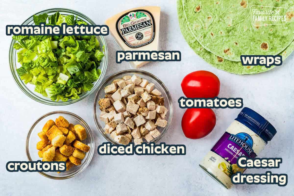 Ingredients to make Chicken Caesar Wraps including vegetable tortillas, parmesan cheese, tomatoes, caesar salad dressing, croutons, chicken and romaine lettuce.