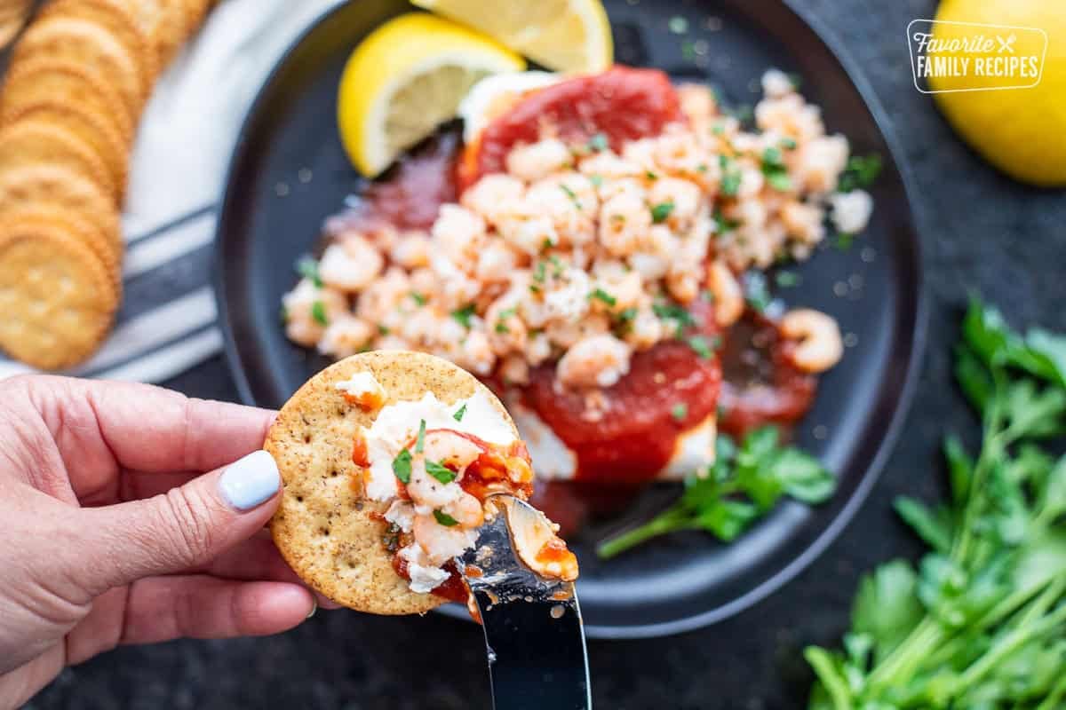 Spreading cream cheese shrimp dip onto a cracker.