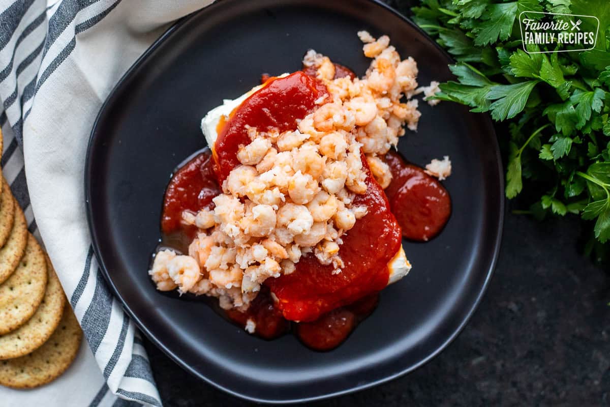 Plate with a brick of cream cheese covered and cocktail sauce and tiny shrimp on top.