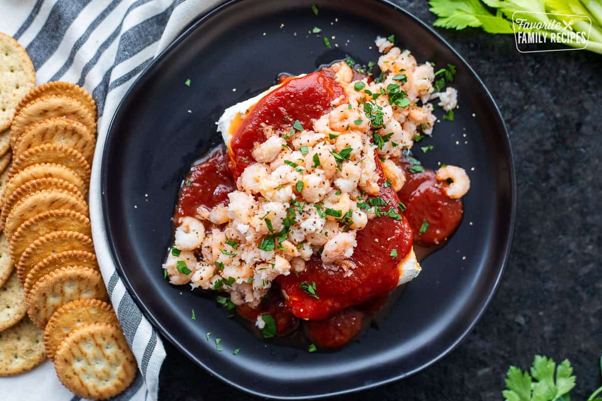 Cream cheese shrimp dip on a plate garnished with parsley and crackers on the side.
