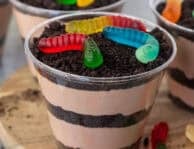Dirt cups with layers of chocolate pudding mixture and crushed Oreos topped with colorful gummy worms.