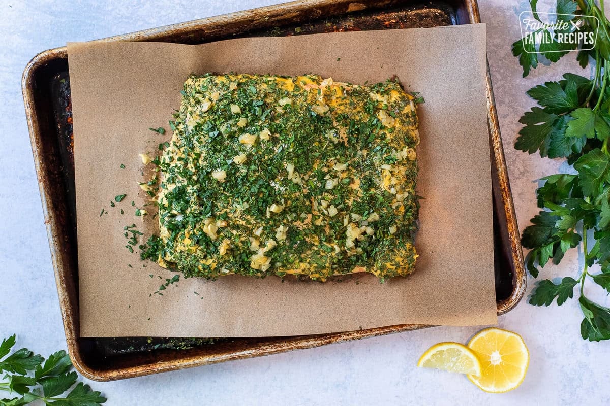 Baked herbed salmon on a small sheet pan lined with parchment paper.