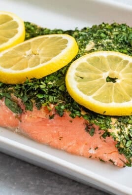 Baked Herbed Salmon on a platter with slices of lemon garnish.